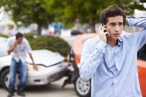 young man on cellphone after car crash