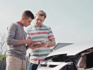 One young motorist swapping insurance details with another mature motorist after a traffic collision.