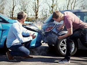 Two Drivers Arguing After Traffic Accident looking at damage
