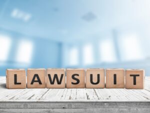 Lawsuit sign on a wooden table in a blurry bright blue room
