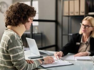 Young woman with neck injury filling documents