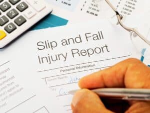 Close up of Slip and Fall injury Form with pen, calculator and writing hand. Concept of Steps to Take After a Slip and Fall Accident