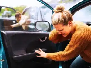 woman driving borrowed car gets in accident is seen exiting the car after injuring her neck. Other driver is seen exiting her car as well.