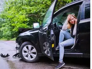 woman is distressed in her crashed car on the road after not knowing what to do after a hit and run car accident.